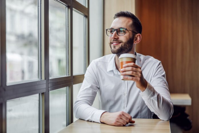young handsome Persona con un cafe en la mano en Madrid mirando por la ventana